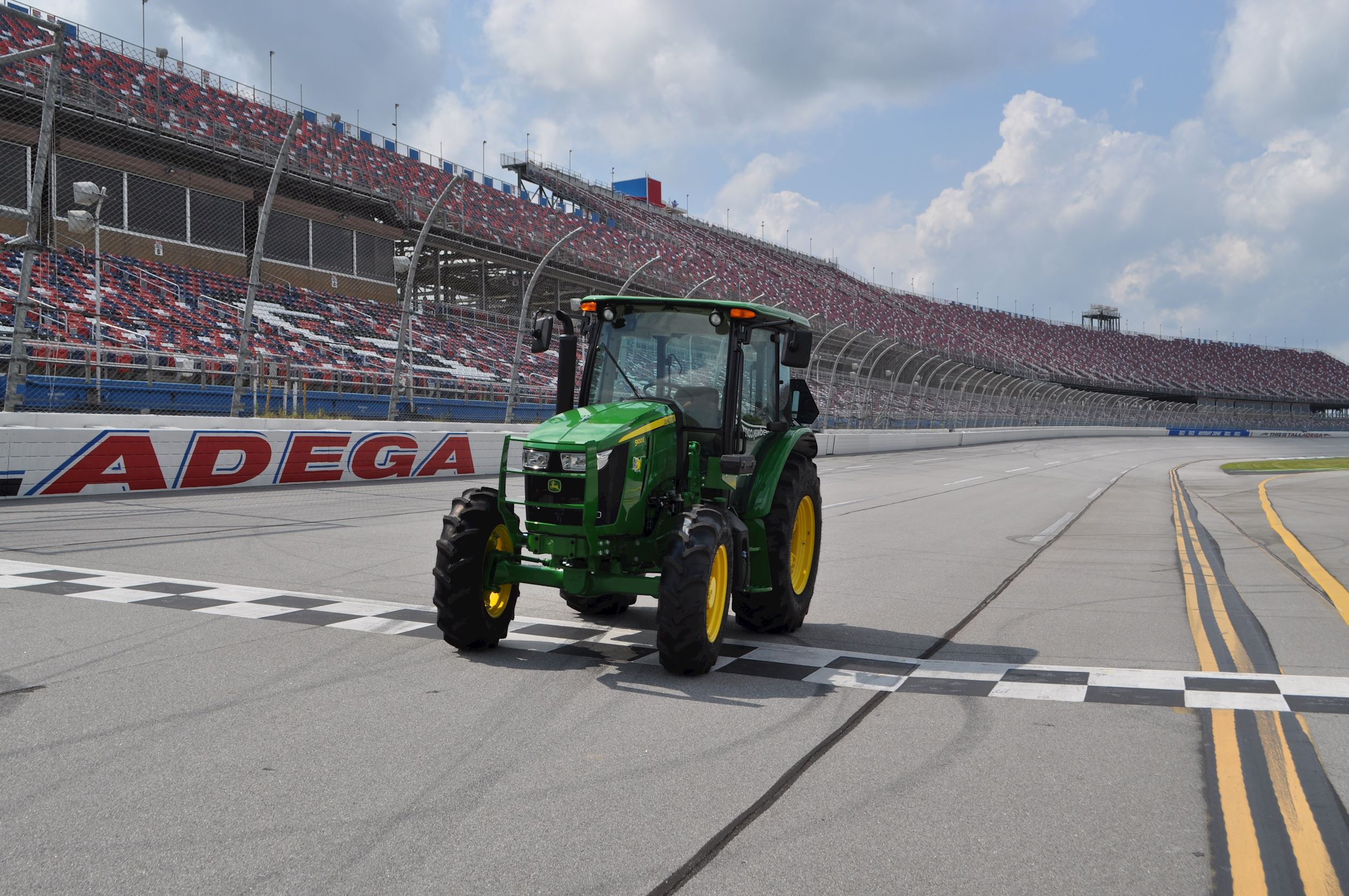 A John Deere 500E tractor drives down the track at Talladega.