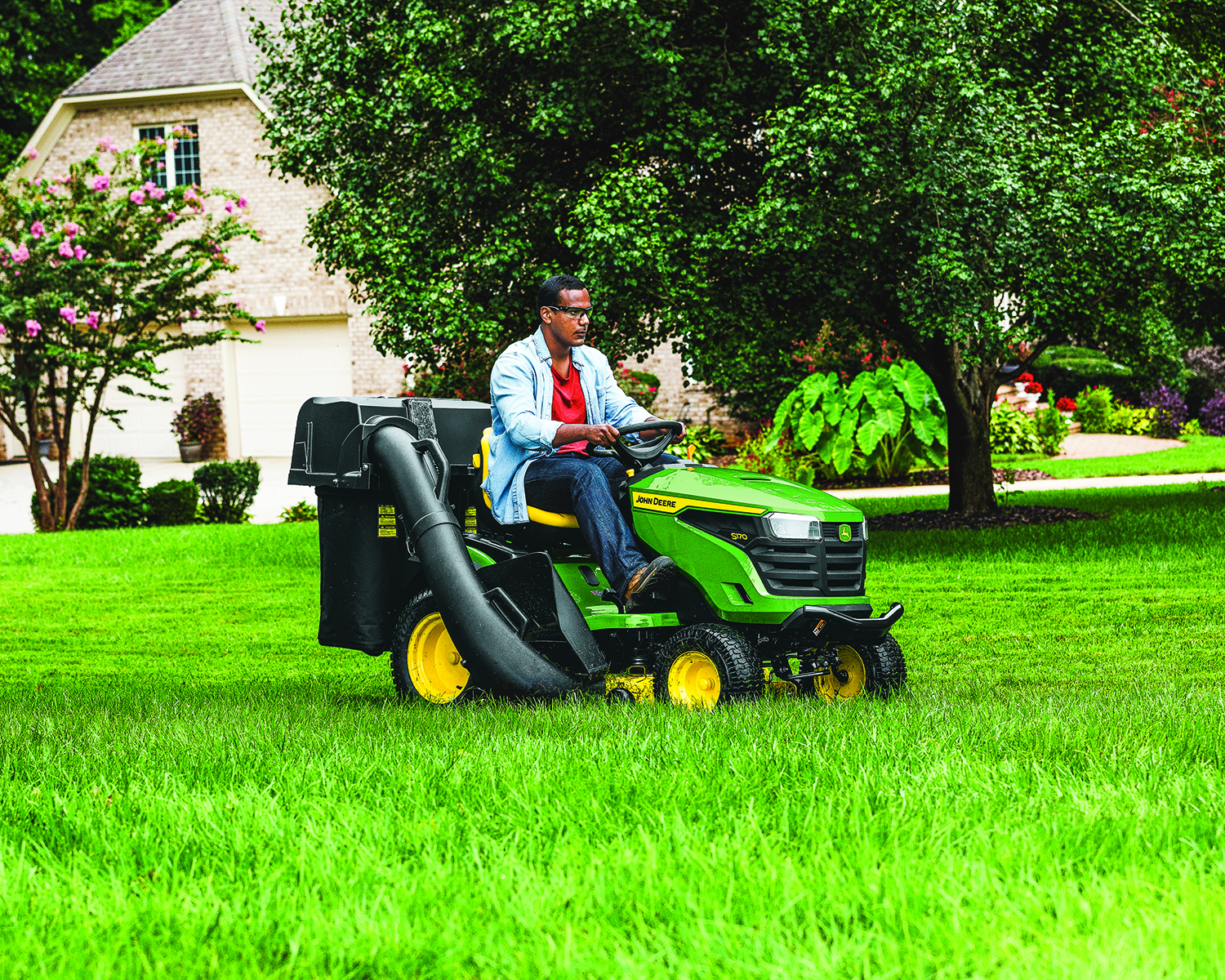 Man mows the grass using a John Deere S170 lawn mower.