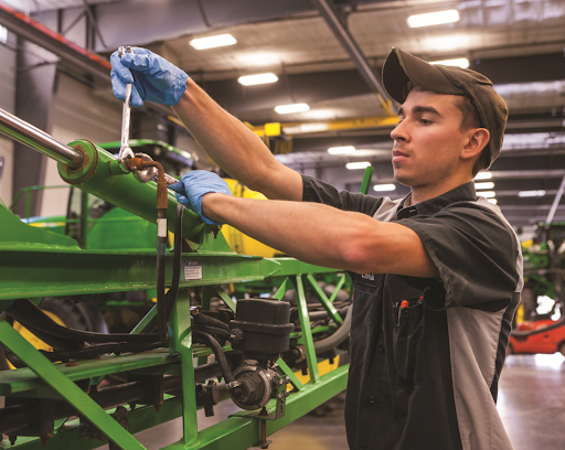 A John Deere service technician works on equipment 