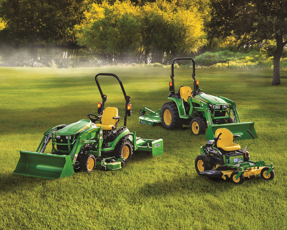 Three John Deere lawn and garden machines on a grassy field: a compact tractor with a front loader a