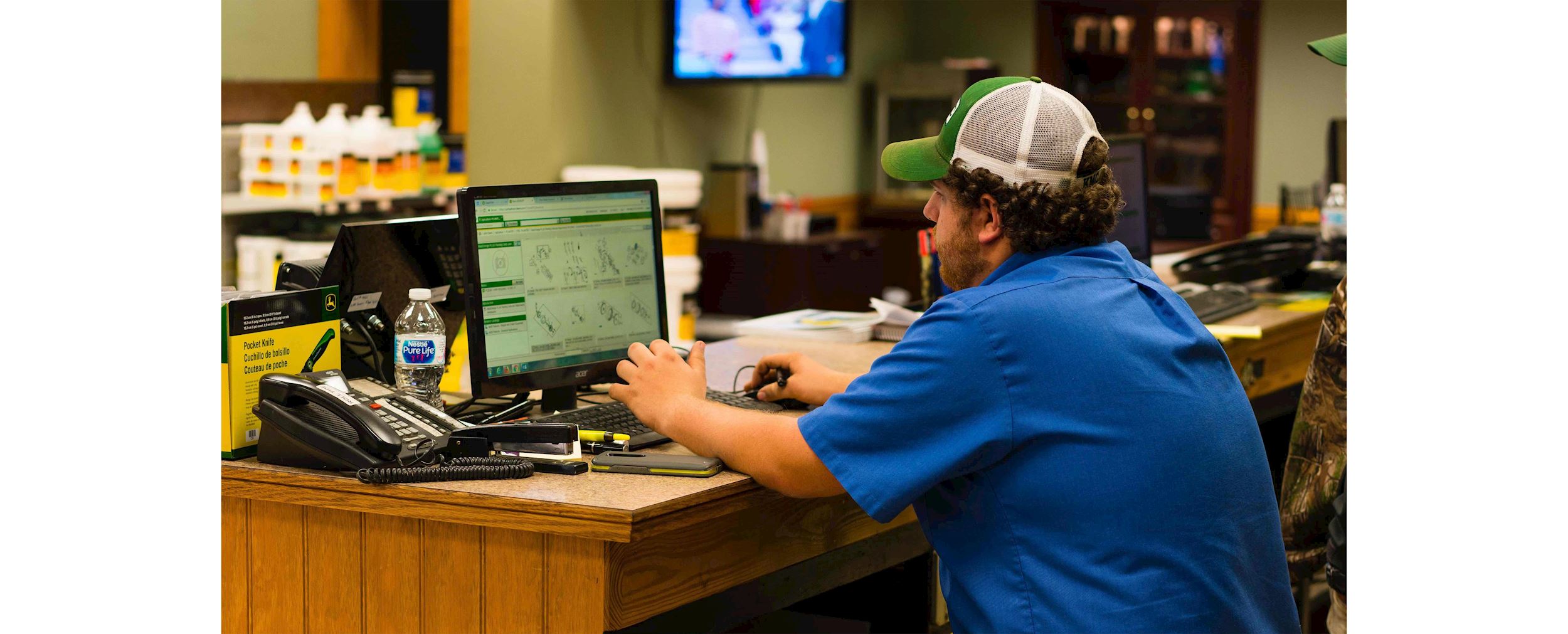 An Ag-Pro employee sits at a computer browsing through John Deere replacement parts online.